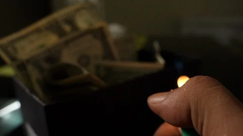 A cigarette lighter emits a flame with dollar bills in a box Stock Footage 109331018