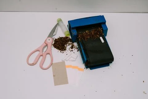 A cigarette rolling tool consisting of a pipe, scissors, papier paper and p.. Stock-Fotos