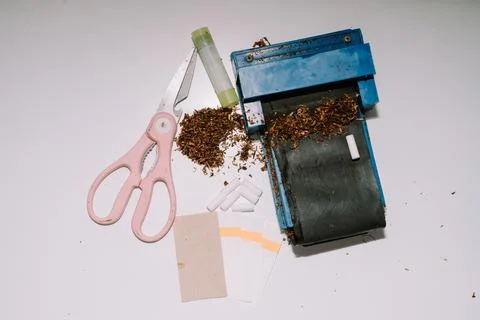 A cigarette rolling tool consisting of a pipe, scissors, papier paper and p.. Foto stock
