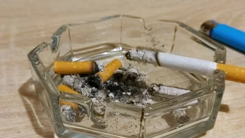 A cigarette smoldering in an ashtray. Timelapse. Cigarette butts in the ashtray Stock Footage 258170057