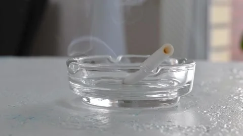 The cigarette is smoldering in a transparent ashtray. Stock Footage 161941118