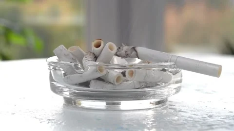 A cigarette smolders in a filled ashtray. Stock Footage 161941117