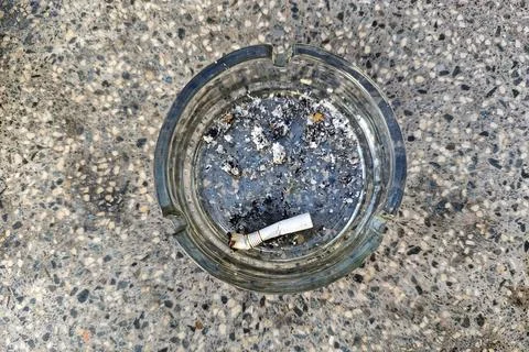 Cigarettes in a glass ashtray, on the table Stock Photos