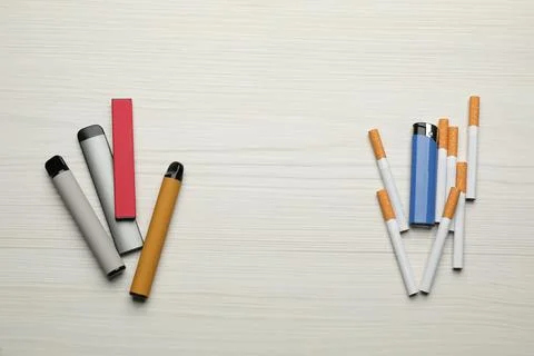 Cigarettes with lighter and different vaping devices on white wooden backgrou Stock Photos