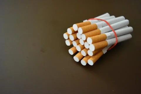 Cigarettes from the pack are fixed with a red rubber band on matte background Stock Photos