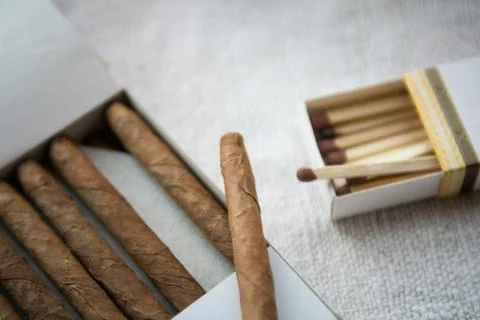 Cigars and whiskey on a light table cloth, one cigar out of the packet Stock Photos