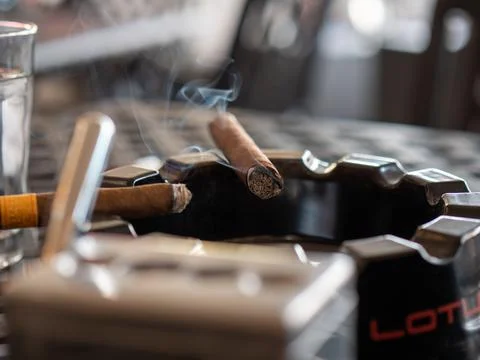 Cigars burning in an ash tray Stock Photos