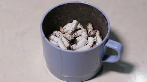 Ciggarette butt in a plastic drinking cup on a white background Stock Footage 194008796