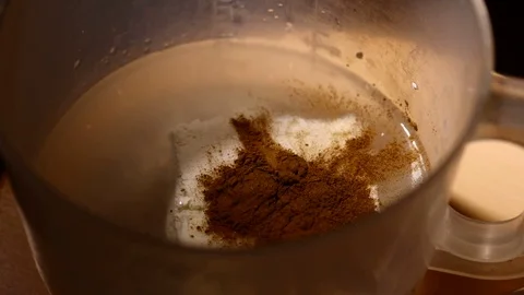 Cinamon powder falling. Close-up of mixer whipping milk smoothie with cinnamon Stock Footage 84021989