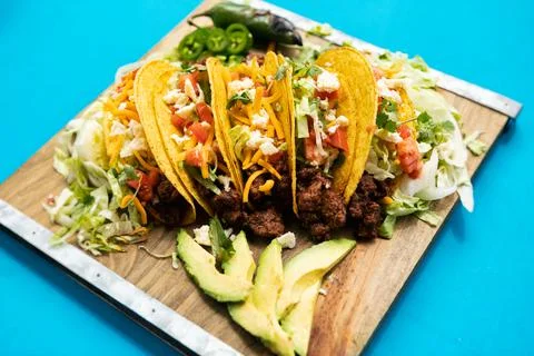 Cinco: Five Tacos On Board With Jalapenos And Avocado Stock Photos