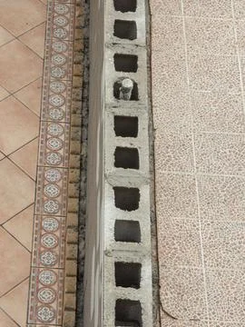 Cinder block wall under construction between tiled patio floors in a home o.. Stock Photos