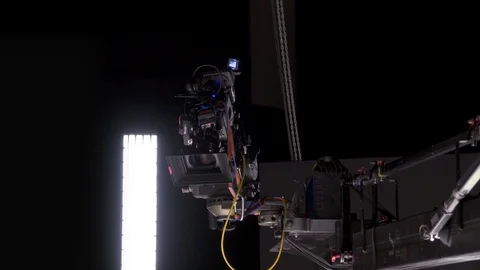 Cinema camera on crane rig being hoisted in dark studio Stock Footage 104056965