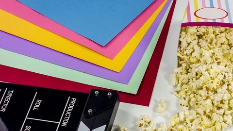 Cinema concept with popcorn, clapperboard, and colored papers. Video stock 76756675