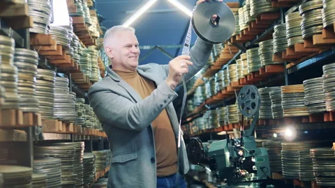 Cinema expert is smiling while looking at old movie tapes. Retro technology Vídeo Stock 158357225