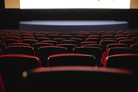 Cinema interior. Chairs in a large empty cinema hall against a white projection Stock Photos