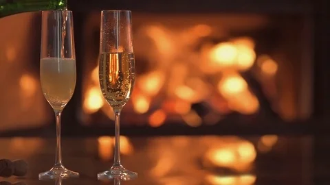 Cinemagraph -Champagne in two glasses on table in front of burning fireplace. Stock Footage 79873654