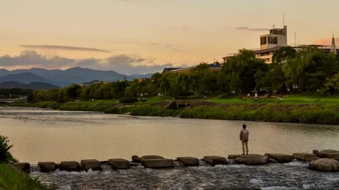 Cinemagraph of dramatic clouds and mellow sunset over river with a lone man. Stock Footage 87491461