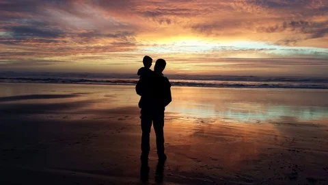 Cinemagraph of father and son on beach in silhouette at sunrise Stock Footage