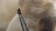 Cinemagraph Of Fireman Standing On High Ladderputting Out Massive Fire Stock Footage