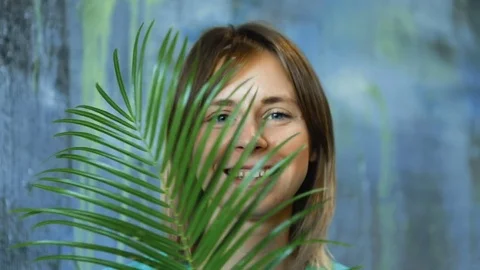 Cinemagraph loop of Charming cheerful blond hair female waves palm leaf Stock Footage 83386568