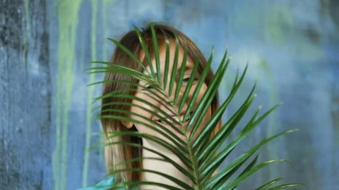 Cinemagraph loop of Charming cheerful blond hair female waves palm leaf Stock Footage 83386973
