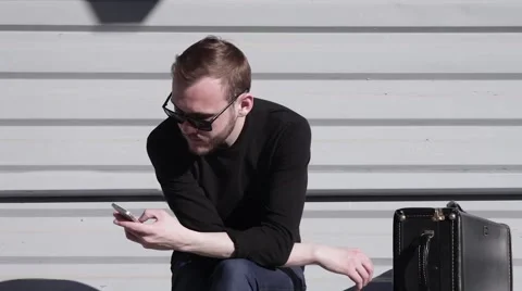 Cinemagraph Loop Handsome Guy in Sunglasses is Typing Text on the Smartphone 66681841