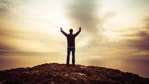 Cinemagraph of man with arms up in praise on mountain top Stock Footage