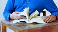 Cinemagraph Of Man Browsing Through Book At Table Stock Footage