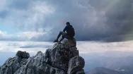 Cinemagraph Of Man Meditating On Mountain Top With Rolling Storm Clouds Stock Footage