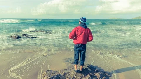 Cinemagraph motion loop offer view of man standing on a rock on the beach Stock Footage 152067295