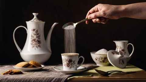 Cinemagraph of a person's hand continuously pouring sugar into a vintage cup Stock Footage 127356578