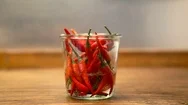 Cinemagraph Of Red Chilis In A Jar With Pouring Water On Wooden Table Stock Footage