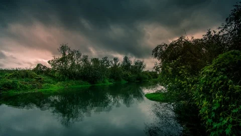 Cinemagraph of a slow river flowing as dark, dramatic storm clouds form Stock Footage 87277480