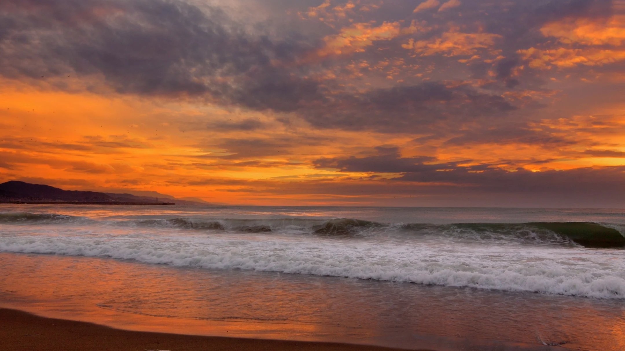 Cinemagraph of waves crashing on beach at beautiful sunset