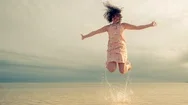 Cinemagraph Of Woman Jumping In Air At Beach In Dress Stock Footage