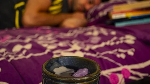 Cinemagraph of young man sleeping with scented candles melting in the foreground Stock Footage 113356780