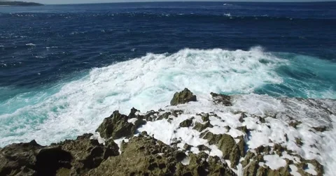 CINEMATIC 4K LOW ANGLE FLY OVER OF BLUE WAVES SPLASHING AGAINST ROCKS Stock Footage 60003334