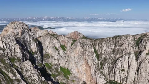 Cinematic 4K UHD Drone Flight Over Rugged Rocky Mountains Above a Sea of Clouds. Stock Footage 342066399