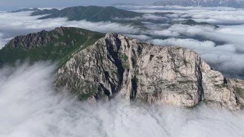 Cinematic 4K UHD Drone Flight Over Rugged Rocky Mountains Above a Sea of Clouds. Stock Footage 342066487