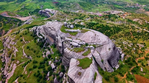 Cinematic Aerial Orbit Around a Massive Rock Formation Over a Green Valley Stock Footage 341272465