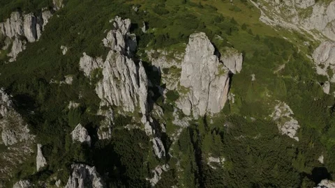 Cinematic aerial pullback from dramatic rock pinnacles revealing a rugged mounta Stock-Footage 324842517