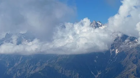 Cinematic aerial of rolling clouds surrounding snow covered Himalayan mountain Stock Footage 336590289