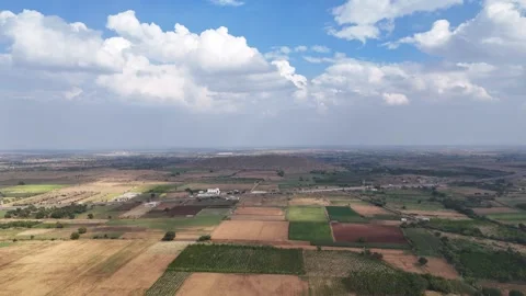 Cinematic aerial view of expansive patchwork farmlands stretching toward the Stock-Footage 335934938