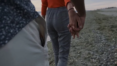 Cinematic angle of couple holding hands while walking on beach Stock Footage 111976959