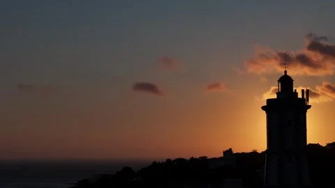 Cinematic backlit view of sunset view behind a silhouette of a lighthouse Stock Footage 315250248