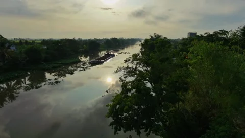 Cinematic cargo barge navigating a reflective countryside river at dawn Vídeos de archivo 336040664