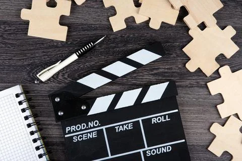 Cinematic  clapper with notepad, pen and puzzle pieces on a table Stock Photos