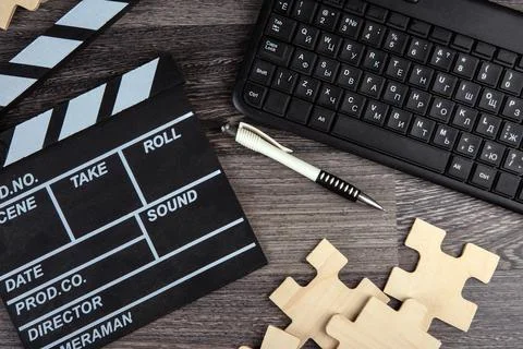 Cinematic  clapper, pc keyboard, pen and puzzle pieces on a table Stock Photos
