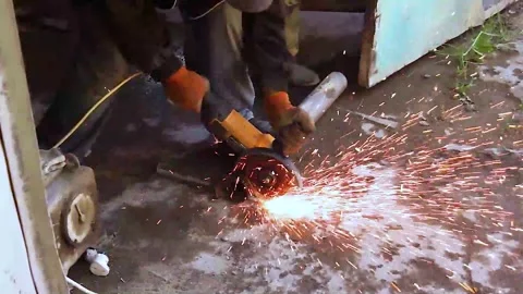 Cinematic close-up of angle grinder cutting metal pipe with intense sparks Stock Footage 325315689