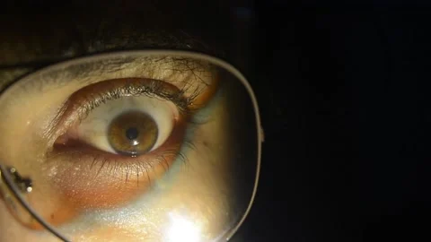 Cinematic Close-Up of an Eye Behind Eyeglasses Expressing Emotion in Warm Light Stock Footage 200799016
